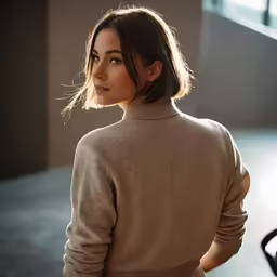 woman in a brown sweater and tan pants posing