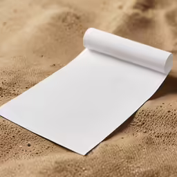 a white paper on top of sand with a pen next to it