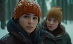 two young women wearing warm clothing are pictured in winter