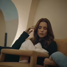 the woman is sitting on a yellow couch