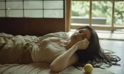 a woman lying in bed next to an apple
