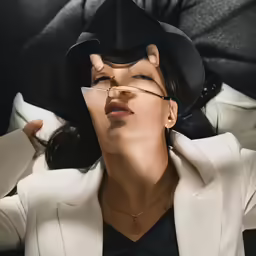 a woman with long black hair and a white suit