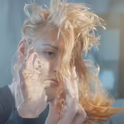 woman holding hands to her face with hair blowing in the wind