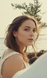 a young woman looking directly into the camera while standing on a beach