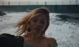 a woman in the rain looking down into the ocean