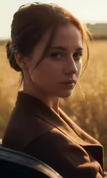 a beautiful woman in a brown top stands by a field