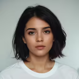a young girl with short black hair is wearing a white t - shirt