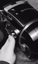 a black and white photo of someone operating an old camera