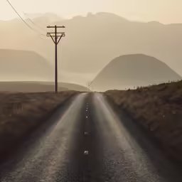 a road in the middle of nowhere with a power line in the background
