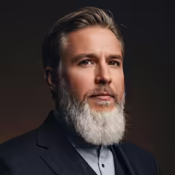 the white - haired man with gray beard and blue shirt