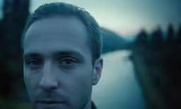 a man staring at the camera outside in the dark