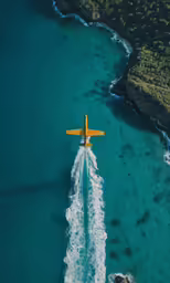 an airplane flying over the ocean with a person standing near it