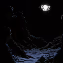 a group of people sit around the dark looking