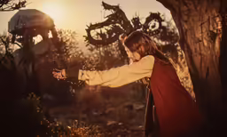 a little girl holds out her hand toward the sun