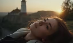 woman sitting on side of hill with light tower in the background