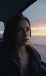 woman sitting inside the back seat of a car looking out the window at the beach