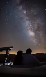 a man and a woman are looking at the night sky