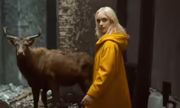 a woman stands next to a brown bull in a building