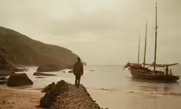 there is a man that is looking at the water and a boat
