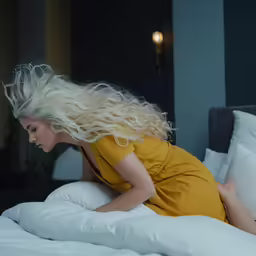 woman with blond hair laying on bed wearing yellow