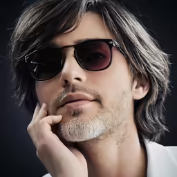a man wearing sunglasses and holding his chin to his ear