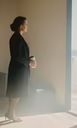 a woman in black and heels standing next to a window