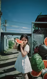 a young girl holding up pieces of watermelon