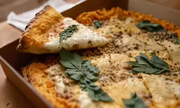 a pizza with leaves on top of it in a box