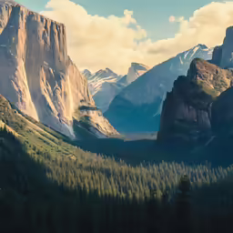 some tall rocky cliffs and trees with clouds in the background