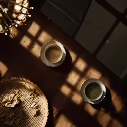 two cups of coffee sitting next to some pastries