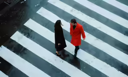 man and woman walking across the street on snowy day