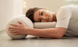 a young lady wearing white laying on a pillow