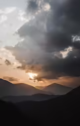 a large hill with clouds and trees under it