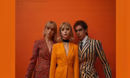 three people in suit and tie posing against a wall