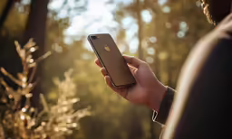 a man holding a cell phone near some trees