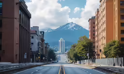 an empty city street with mountains and buildings in the background