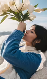 a woman is laying on the ground holding a bunch of flowers