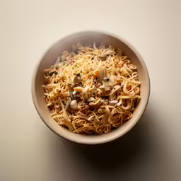 a bowl filled with noodles and nuts on top of a white surface