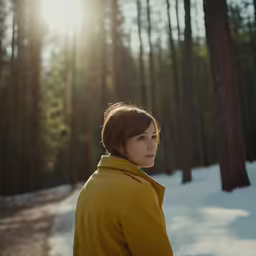 the young woman is standing in a forest