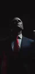 the man is wearing a red tie and black suit