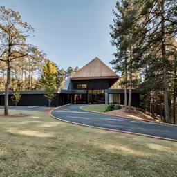 an exterior view of a black and brown house with a driveway