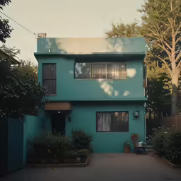 a big teal house with some plants in the yard