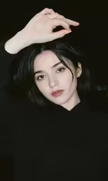an asian woman in black shirt holding her hand over her head