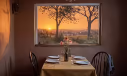 a table set for dinner with the sunset on the window