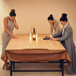 two ladies standing at a table and one is touching her face