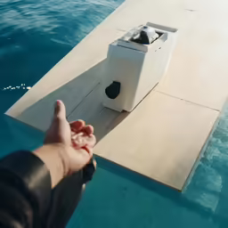 a person pointing at an empty box next to the water