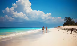 two people walking on a beach with the ocean in the background