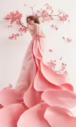 a model wears a pink wedding dress in front of cherry blossom blossoms