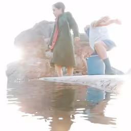 two women standing next to each other holding water cans