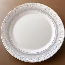 white plate with spiky edges, against a brown tablecloth